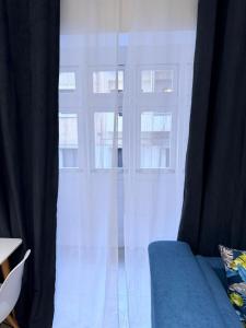a window with white curtains and a blue couch at The White Balcony in Il-Gżira