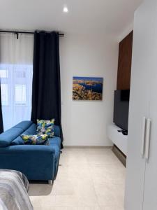 a living room with a blue couch and a tv at The White Balcony in Il-Gżira +15 photos