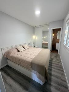 a white bedroom with a large bed and a mirror at Central Suites Silgar Sanxenxo in Sanxenxo