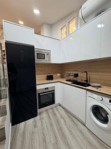 a kitchen with white cabinets and a washer and dryer at Central Suites Silgar Sanxenxo in Sanxenxo