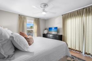 a bedroom with a white bed and a television at Boardwalk Unit A4 in Pensacola Beach