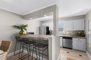 a kitchen with white cabinets and a island with bar stools at Boardwalk Unit A4 in Pensacola Beach