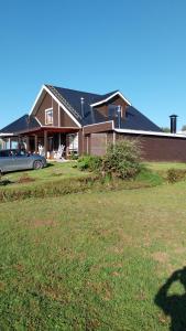 a house with a car parked in front of a yard at Casa Halcon de Lagunitas in Puerto Montt