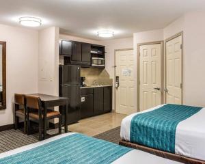a hotel room with a bed and a desk and a kitchen at Suburban Studios Avondale in Avondale