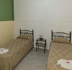 two beds in a room with a side table at Hotel San Martín in Santa Rosa