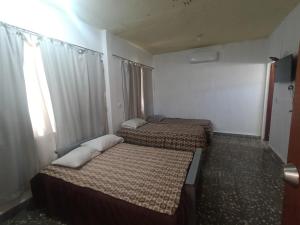 two beds in a small room with a window at Casa Emilio Carranza, Linares in Linares