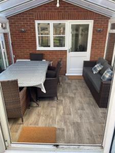 a patio with a table and chairs and a couch at New Forest Home in Hordle +10 photos