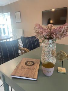 a table with a vase with flowers and a wooden cutting board at Ferienwohnungen Seeglück in Senftenberg