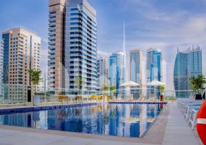 a swimming pool in a city with tall buildings at Staymora Suites in Dubai