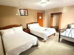 a hotel room with two beds and a chair at Hostal Casa Grande in Quito