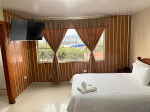 a bedroom with a bed and a tv and a window at Hostal Casa Grande in Quito