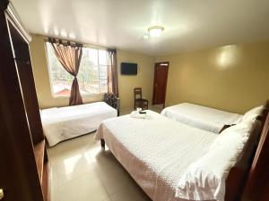 a hotel room with two beds and a window at Hostal Casa Grande in Quito