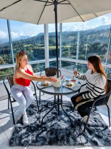 two women sitting at a table with an umbrella at Hotel Alta Montaña Mongui By Seres Viajeros in Monguí