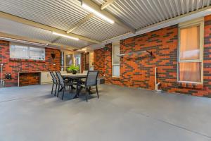 a dining room with a table and a brick wall at Relax Refresh Rejuvenate Pool Cabin Garden Tree house Vintage charm in Berwick