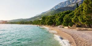 a beach with people sitting on the shore at House Nikola in Tučepi