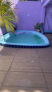 a hot tub in a yard with a purple wall at Hostel Namastê in Maceió