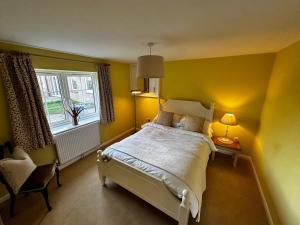 a yellow bedroom with a bed and a window at The Potting Cottage in Tydd Saint Giles