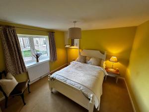 a yellow bedroom with a bed and a window at The Potting Cottage in Tydd Saint Giles