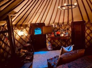 a room with a yurt with a couch and a tv at Esk Yurt in Drummelzier