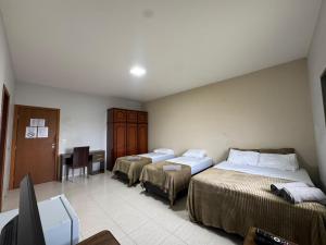 a room with two beds and a television in it at Alvorada Hospedagem in Jataí +12 photos
