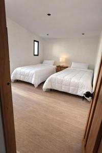 two beds in a room with white sheets at Casa Olivos in Ciudad Vieja