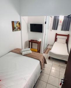 a room with two beds and a tv in it at Pousada Torre dos Mouros in Pirenópolis