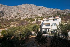 een wit huis met een berg op de achtergrond bij Apartments Lianto in Drasnice