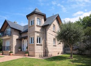 a large brick house with a tower at VILLA PANGEA Habitaciones Boutique - Camino del Norte - Castro Urdiales in Castro-Urdiales