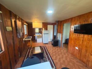 a living room with wooden walls and a kitchen at Cabañas costa rio imperial in Quillén