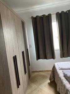 a bedroom with a wooden cabinet and a window at Casa dá Jo in Rio das Ostras