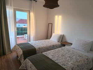 two beds in a hotel room with a window at Casa da Baleia Ericeira in Ericeira