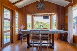 a dining room with a table and chairs and a clock at Hostal refugio nomada in Puerto Montt