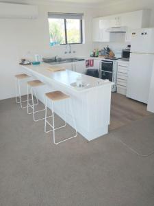 a kitchen with a white counter and stools at Shoal Bay Water Views, 1 night stays available in Nelson Bay