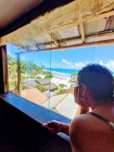 a woman looking out of a window at the ocean at MistiHouse Surf & Amor con vista al mar a 50 mts de la playa in Itacaré