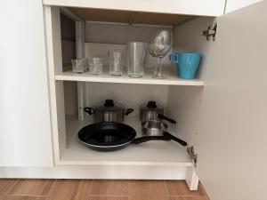 a kitchen cabinet with a frying pan and glasses at La Casa de Nido-Cozy Studio in Veszprémfajsz +1 photo