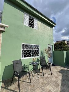 a patio with two chairs and a table in front of a green building at Condomínio Central Sobradinho in Uruguaiana