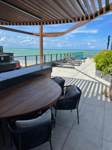 a wooden table and chairs with a view of the beach at Garden Haus - Flat beira mar in João Pessoa