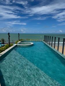 a swimming pool with the ocean in the background at Garden Haus - Flat beira mar in João Pessoa