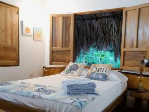 a bed with towels on it in a room with a window at La Coralina azul in San Bernardo del Viento