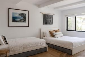 a white bedroom with two beds and a window at Bay Properties Bridgewood in Yamba