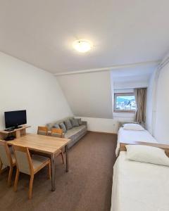 a room with two beds and a table and a couch at Apartments Konaci BOOKING in Kopaonik