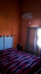 a bedroom with a bed with a striped comforter and a window at Complejo Aura in Colón