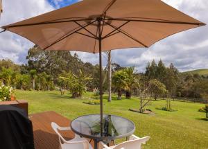 a glass table with an umbrella on a deck at The Shack in Mangonui