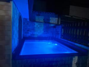 a swimming pool with blue lights in a room at Casas do Pescador in Maricá