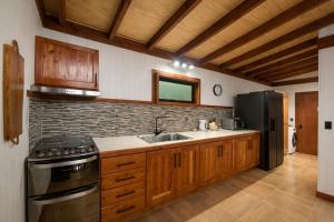 a kitchen with a sink and a stove and refrigerator at Refugio Matteo&Colo Sur de Chile in Panguipulli +12 photos