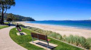 two people sitting on a bench at the beach at Whimsy Cottage, Beachside retreat, Outdoor bath in Kingston Beach
