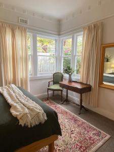 a bedroom with a bed and a desk and windows at Whimsy Cottage, Beachside retreat, Outdoor bath in Kingston Beach