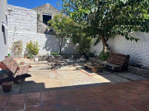 a patio with two benches next to a white wall at Habitacion Privada, Single Room in Paysandú