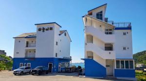 a white and blue building with cars parked next to it at Geoje Haneul Ari Pension in Geoje