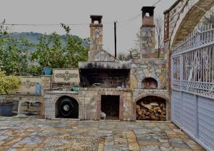 a stone fireplace in a yard with a fence at Guesthouse Aloe in Berat